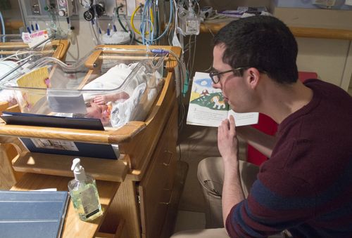 Derek MacMath reads to a baby
